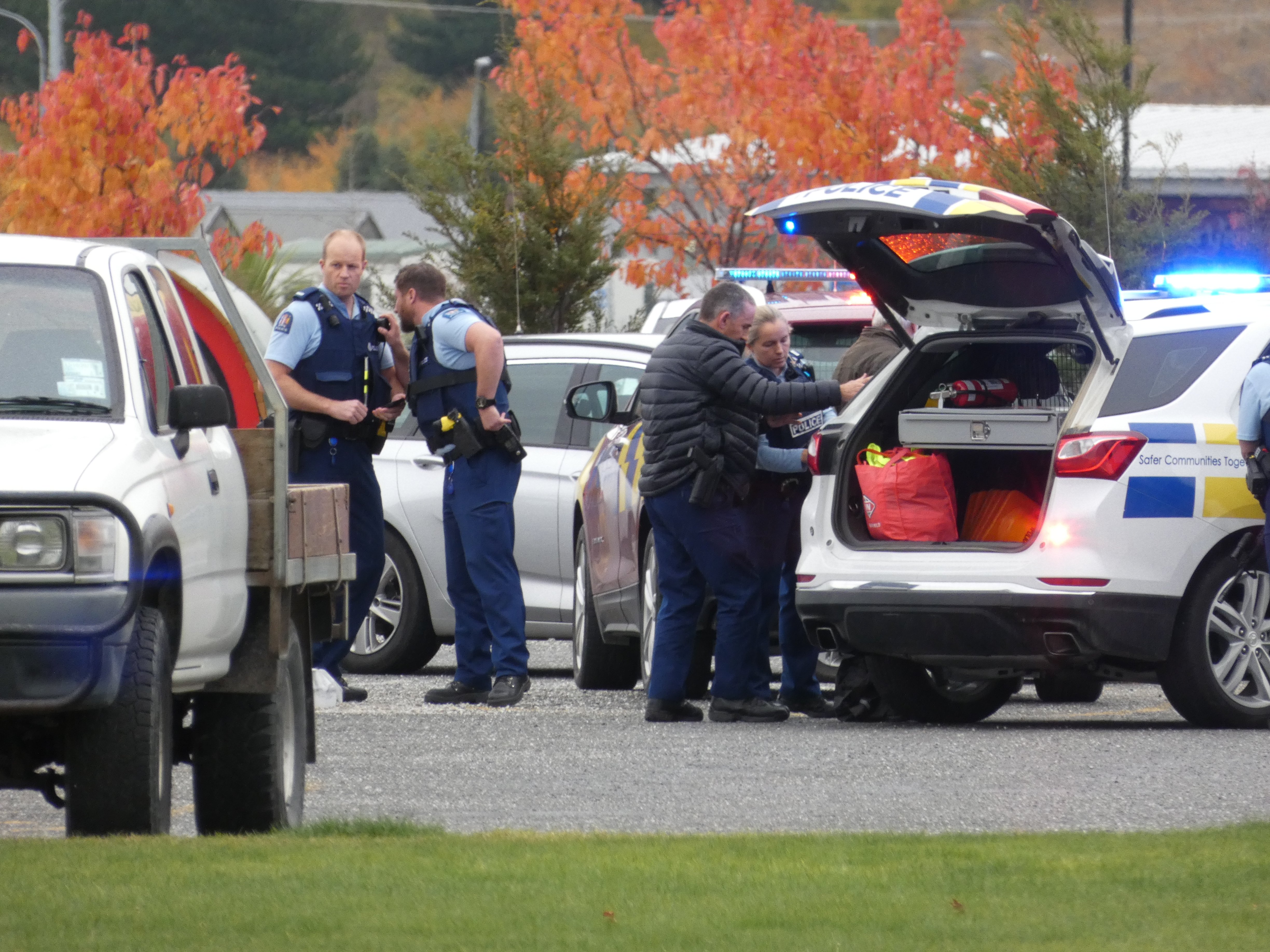 Police officers escort a 59-year-old man (obscured) wanted in relation to family harm and...