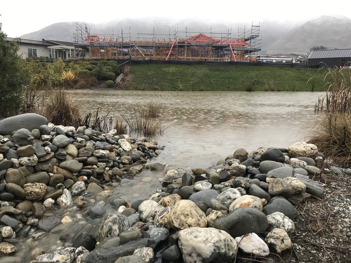 Water overflows from the Alpha Series One stormwater pond into the Otago Fish & Game wetlands and...