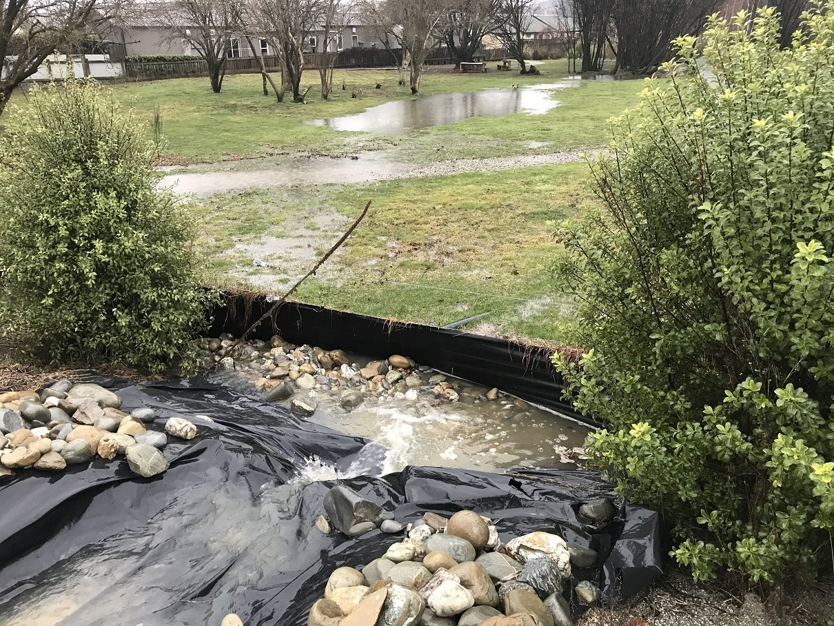 Water overflows from the Alpha Series One stormwater pond into the Otago Fish & Game wetlands and...