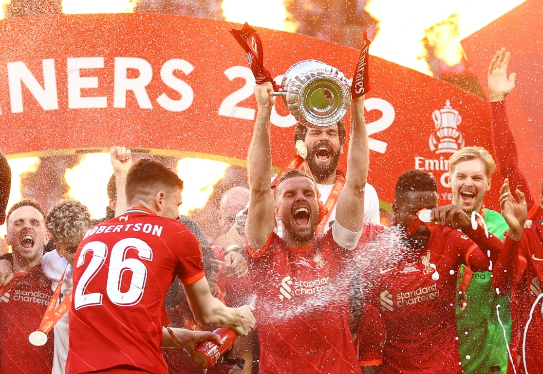 Liverpool captain Jordan Henderson lifts the trophy as the team celebrate after winning the FA...