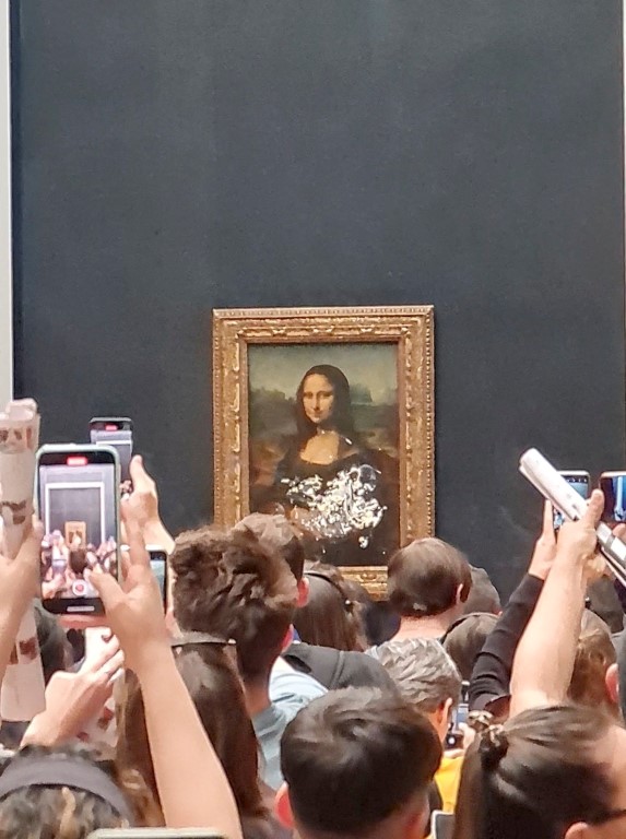Visitors take pictures and video of the Mona Lisa after cake was smeared on the protective glass...