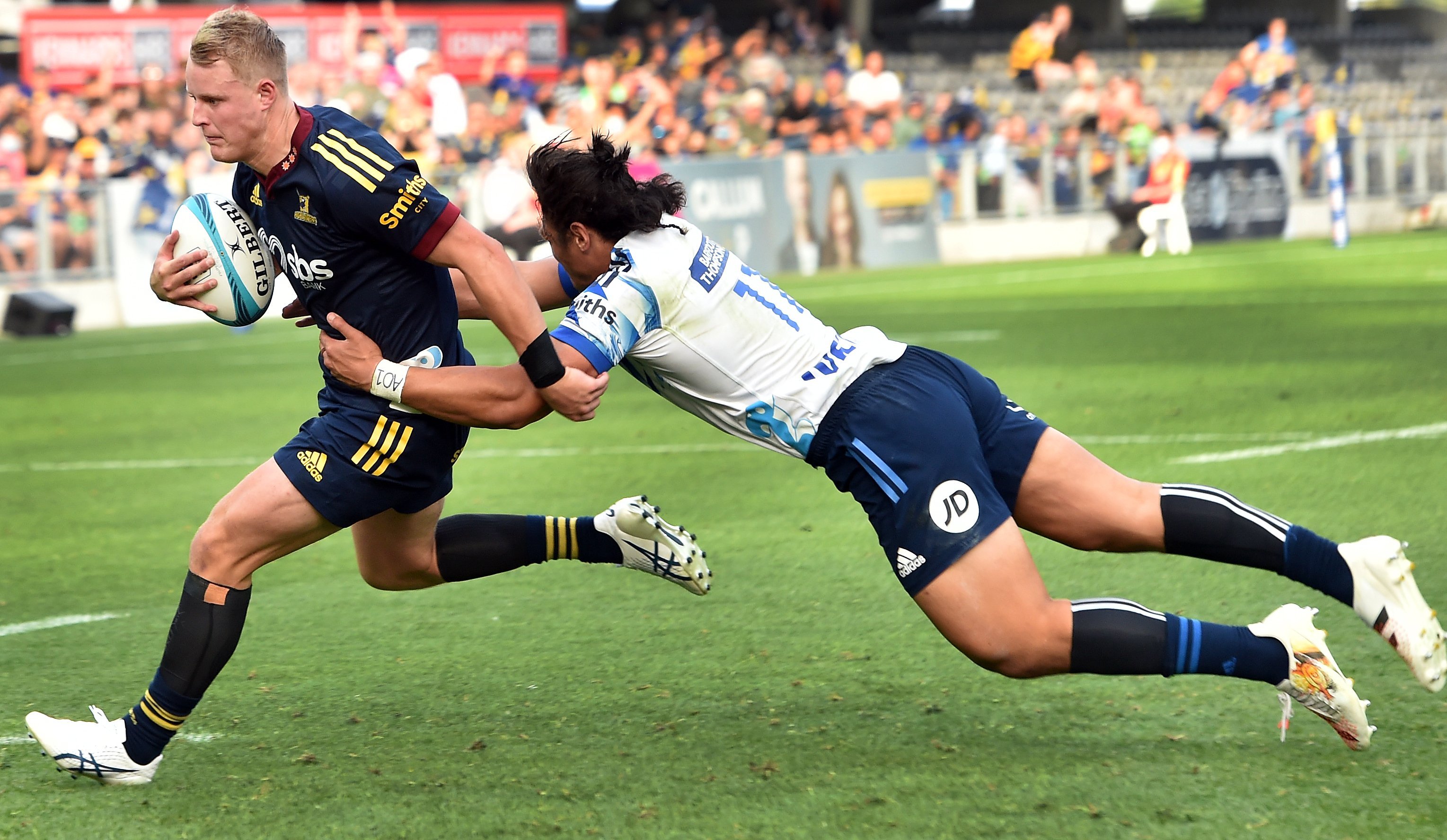 Highlander Sam Gilbert is held by Blues' Caleb Clarke to score a try during their March Super...