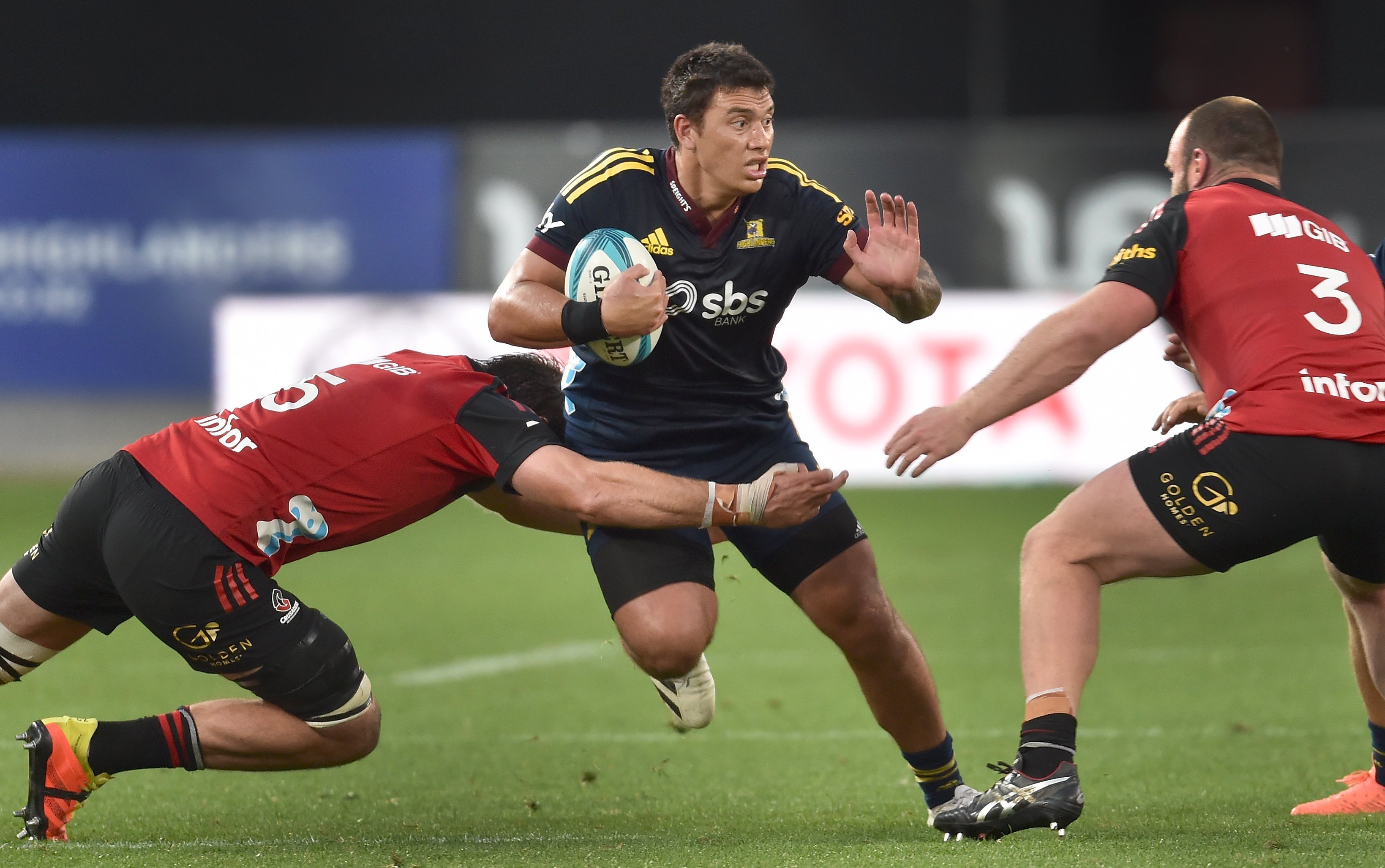 Highlanders midfielder Thomas Umaga-Jensen tries to get past Crusaders forwards Sam Whitelock ...