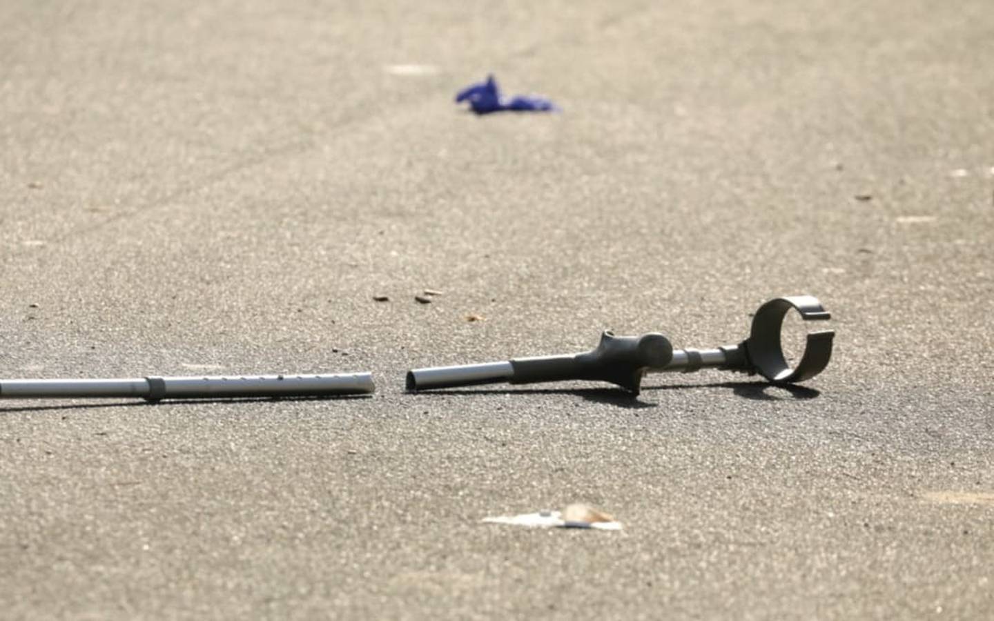 A broken crutch lies near the scene of the stabbing. Bystanders, including one wielding a crutch,...