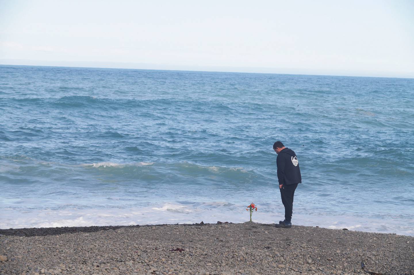 A man stands near the bouquet of flowers placed on the beach at Goose Bay, the day after the...