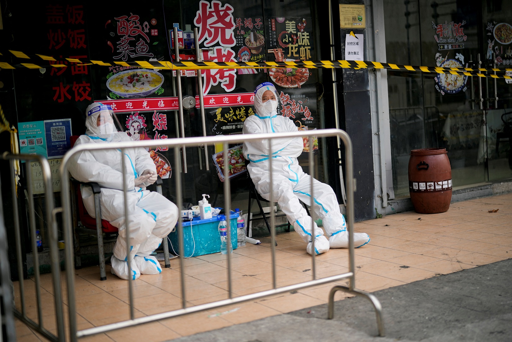 Workers in protective suits keep watch behind a barrier at a sealed restaurant area. Photo: Reuters