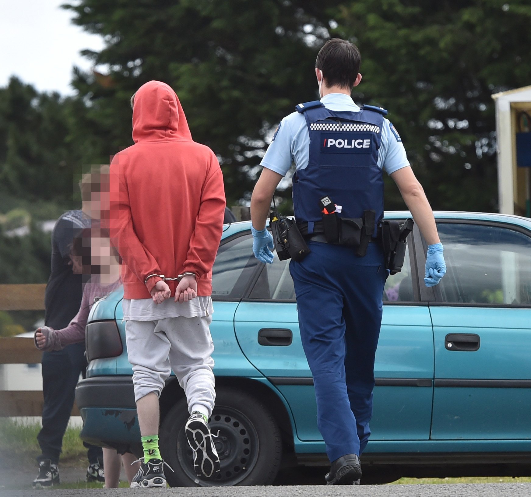 A police officer walks with a youth in handcuffs at the intersection of Riselaw Rd and...