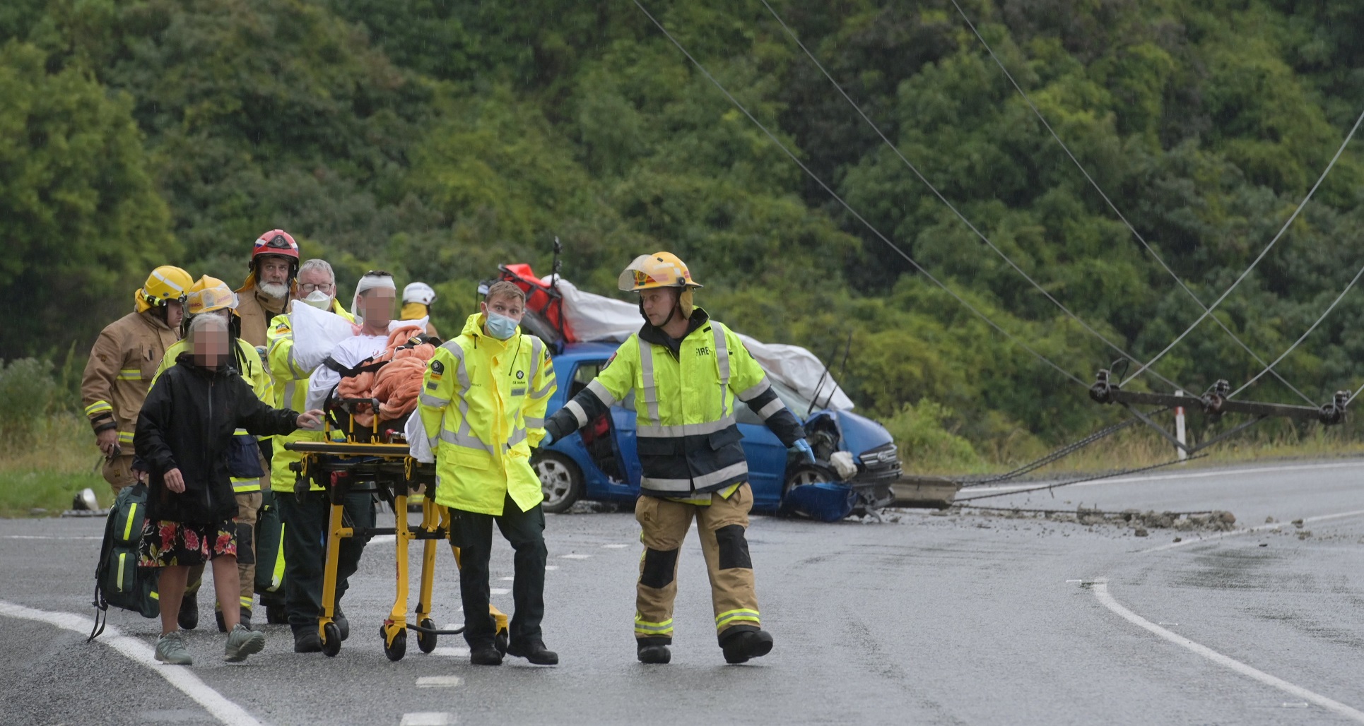 Emergency services wheel a stretcher containing a seriously injured man to a waiting ambulance,...