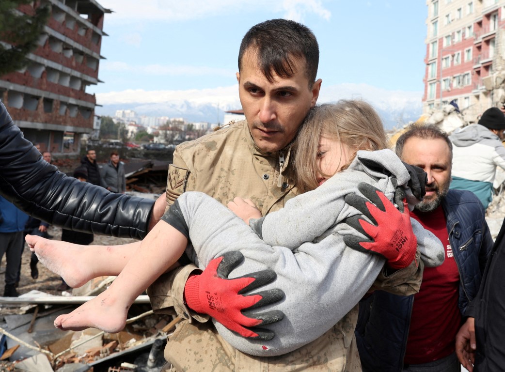 A child is carried out by a rescuer from the site of a damaged building following an earthquake...