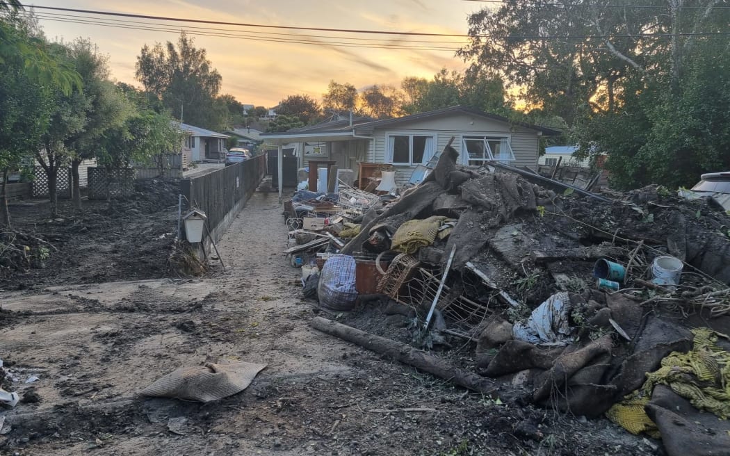 Belongings and furniture that were contaminated by floodwaters are piled up on a street in...