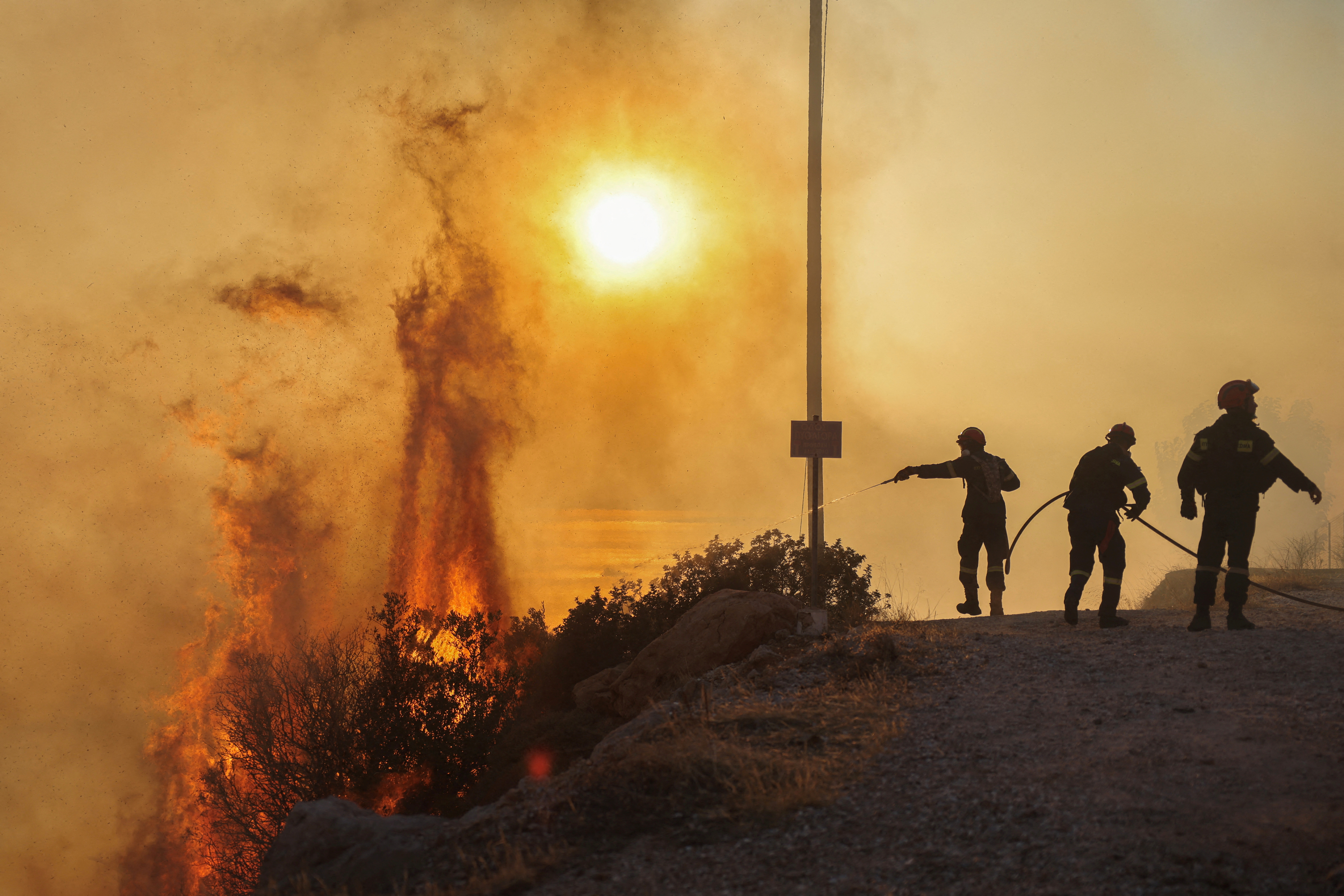 Firefighters try to put out a wildfire burning in Saronida, near Athens, on Monday. Photo: Reuters