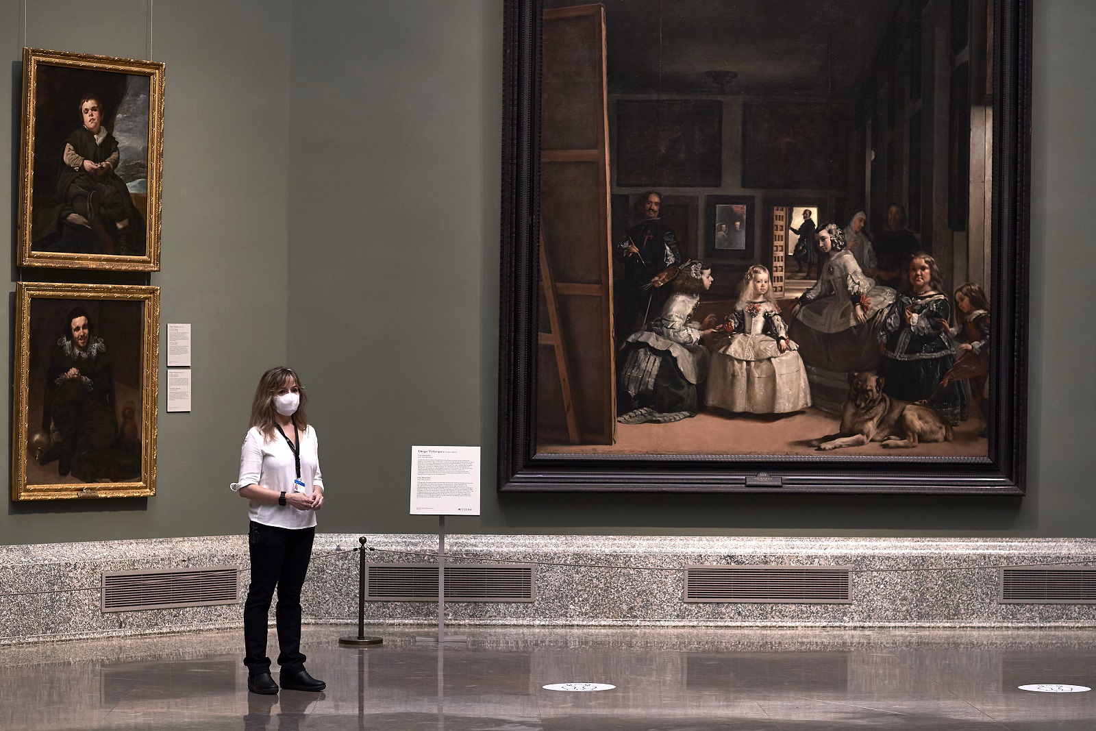 A museum worker wearing a facemask stands next to Las Meninas, by Spanish painter Diego Velazquez...