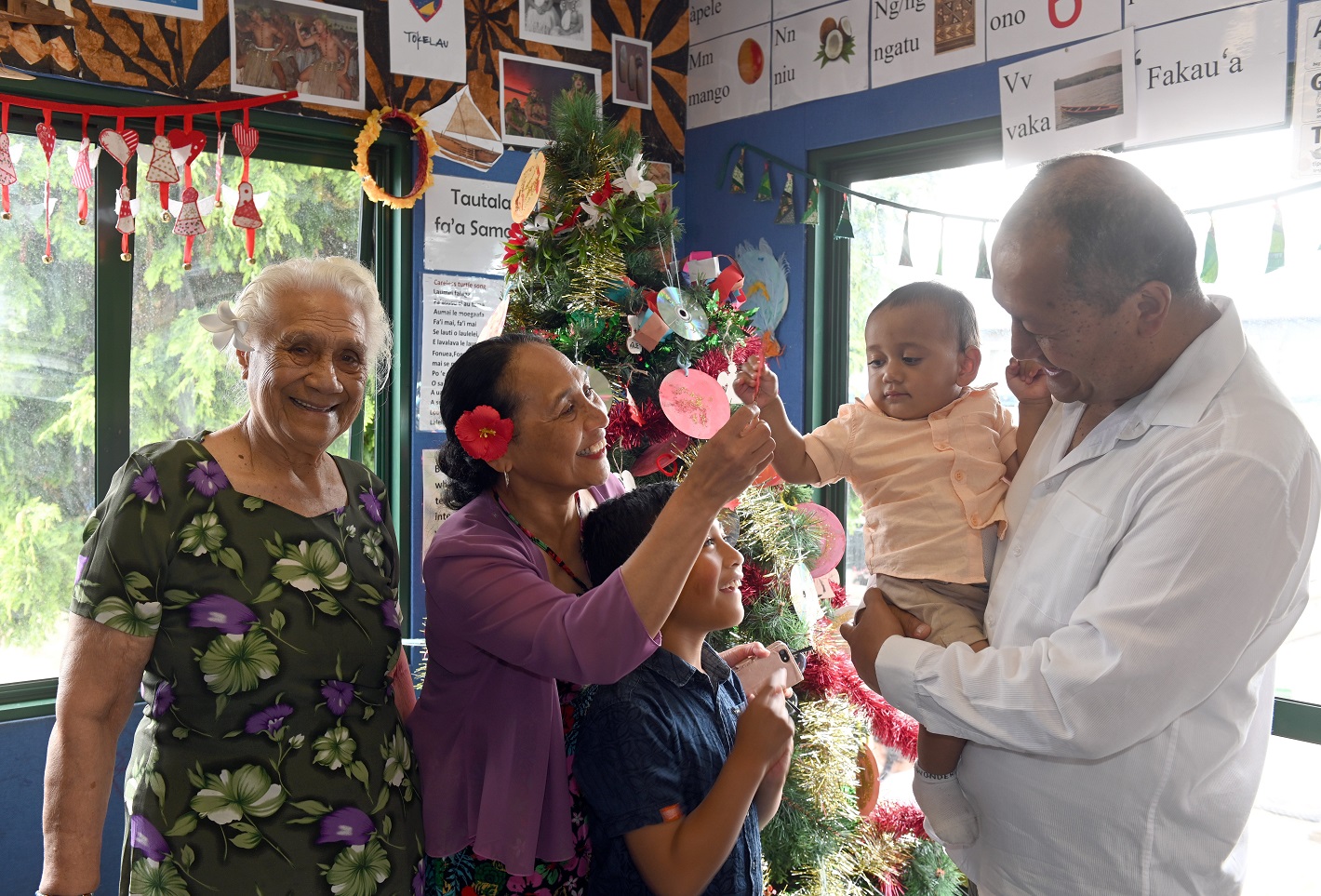 Finau Taungapeau (second from left) helps decorate the Christmas tree with (from left) her mother...