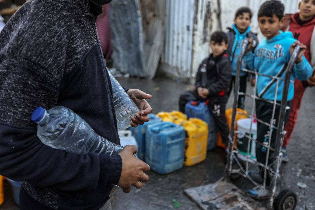 Palestinians carry containers of drinkable water collected from mobile barrels. UNRWA has been...