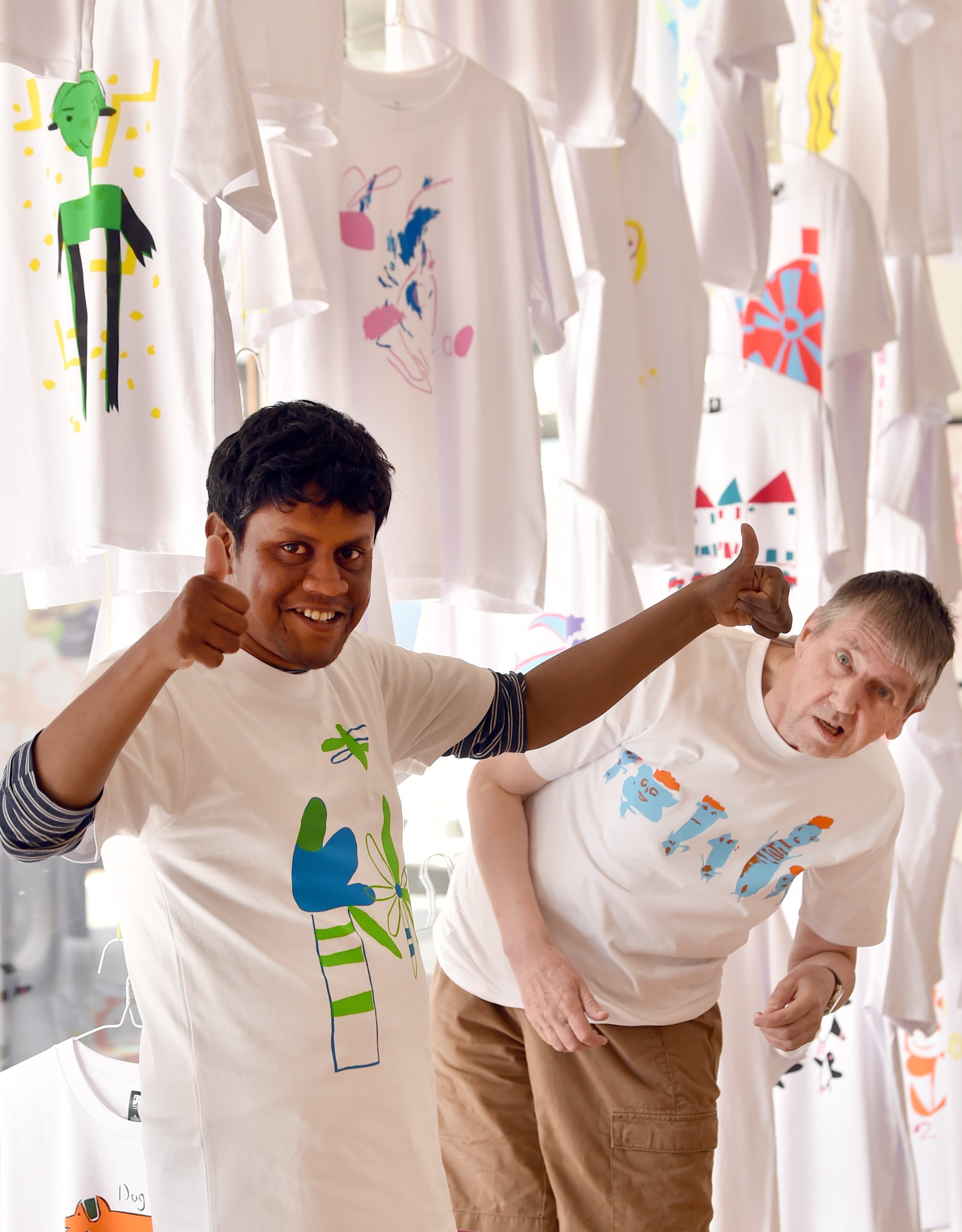 Artists Ebenezer Shodavarian (left) and Owen Palmer display an array of original printed T...