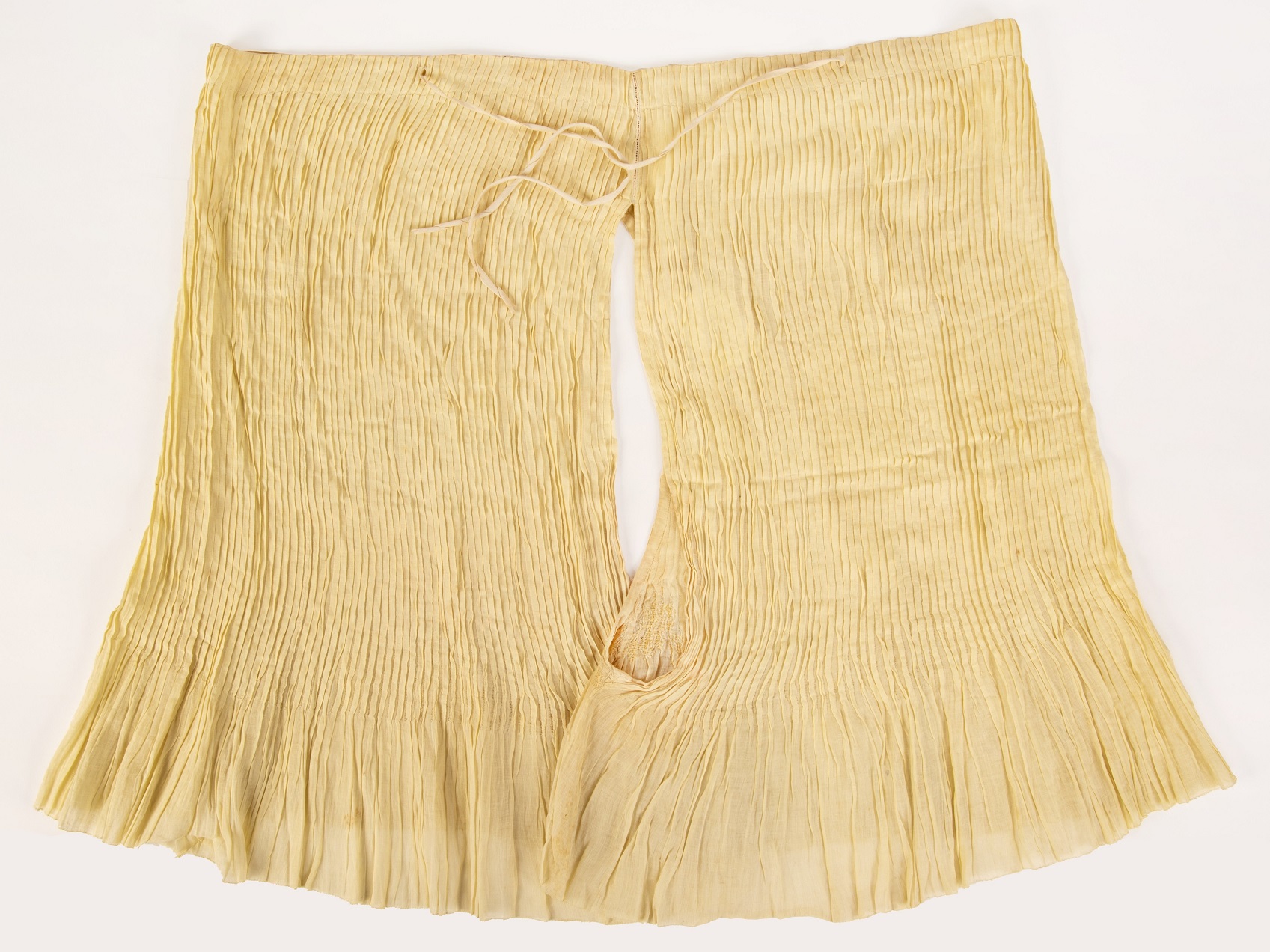 Pale-yellow open-crotch knickers shaped by vertical tucks and drawstring at waist and darned on...
