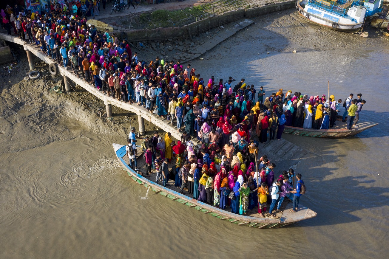 Crowds of climate migrant workers cross the Poshur river in Bangladesh to work in an export...