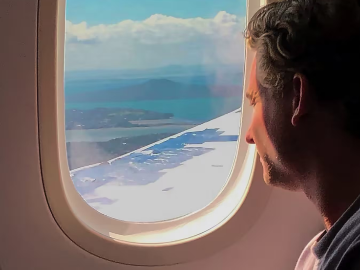 A passenger on a Latam Airlines flight looks out a window at the plane's wing heavily covered in...