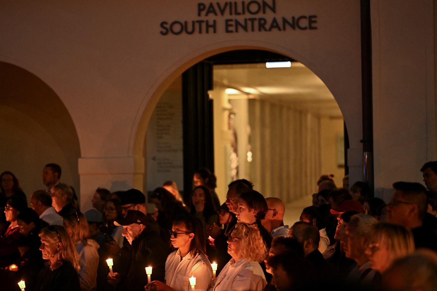 People hold candles during the a candlelight vigil in Sydney for the victims of the Bondi...