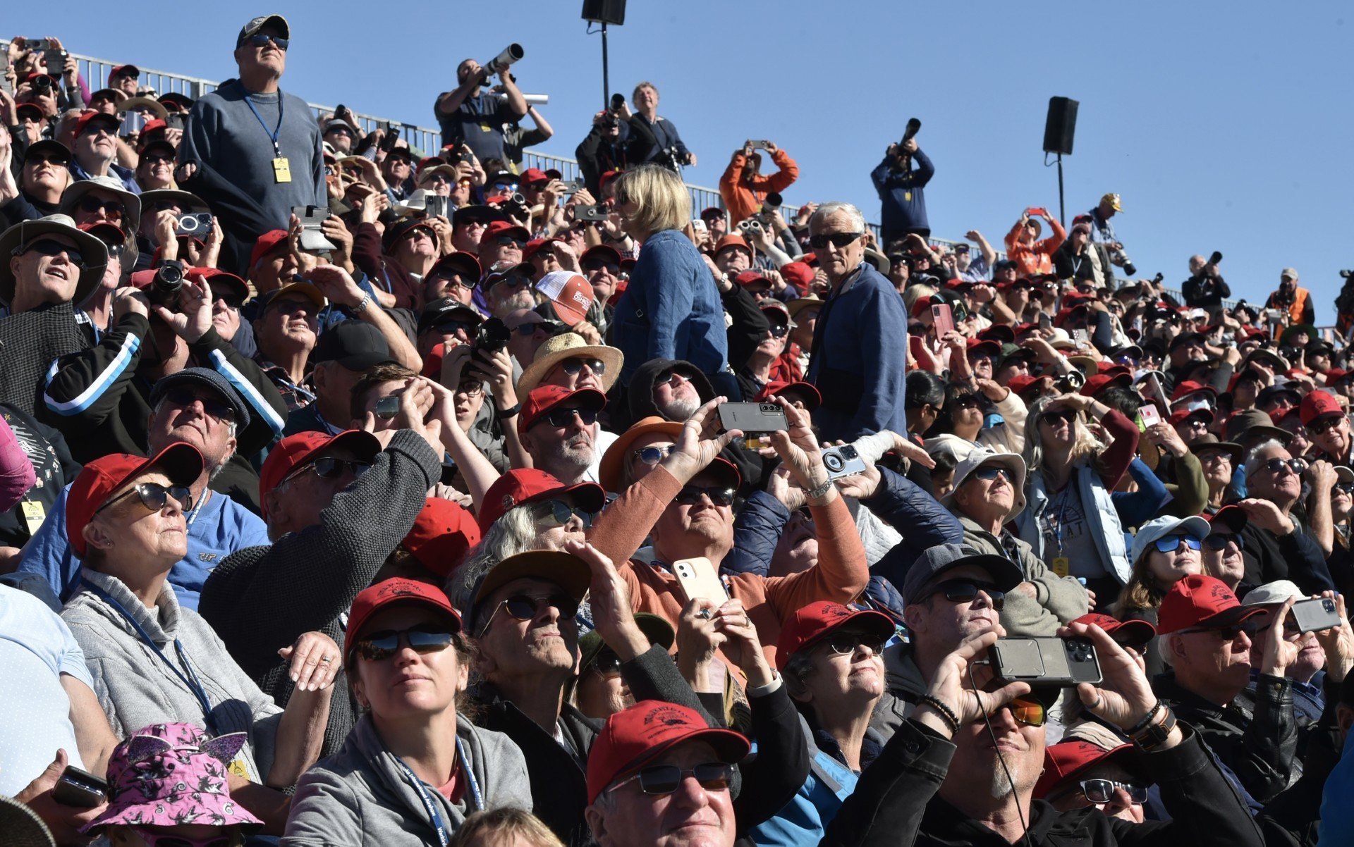Some of the 70,000 spectators track a USAF F-16 jet through the sky at Warbirds over Wanaka over...