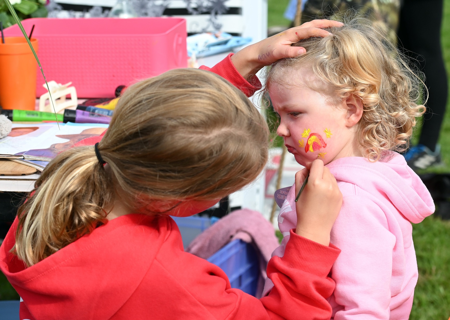 Isla McLay, 9, of Waitati, paints a rainbow and sparkles on the cheek of Safari Kirby, 2 and a...