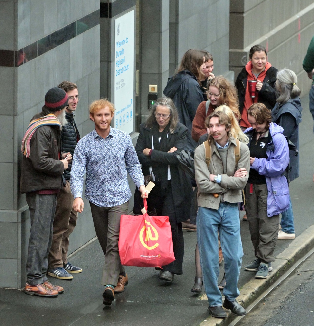 Climate activist Adam Currie (centre left) leaves the Dunedin District Court with supporters...