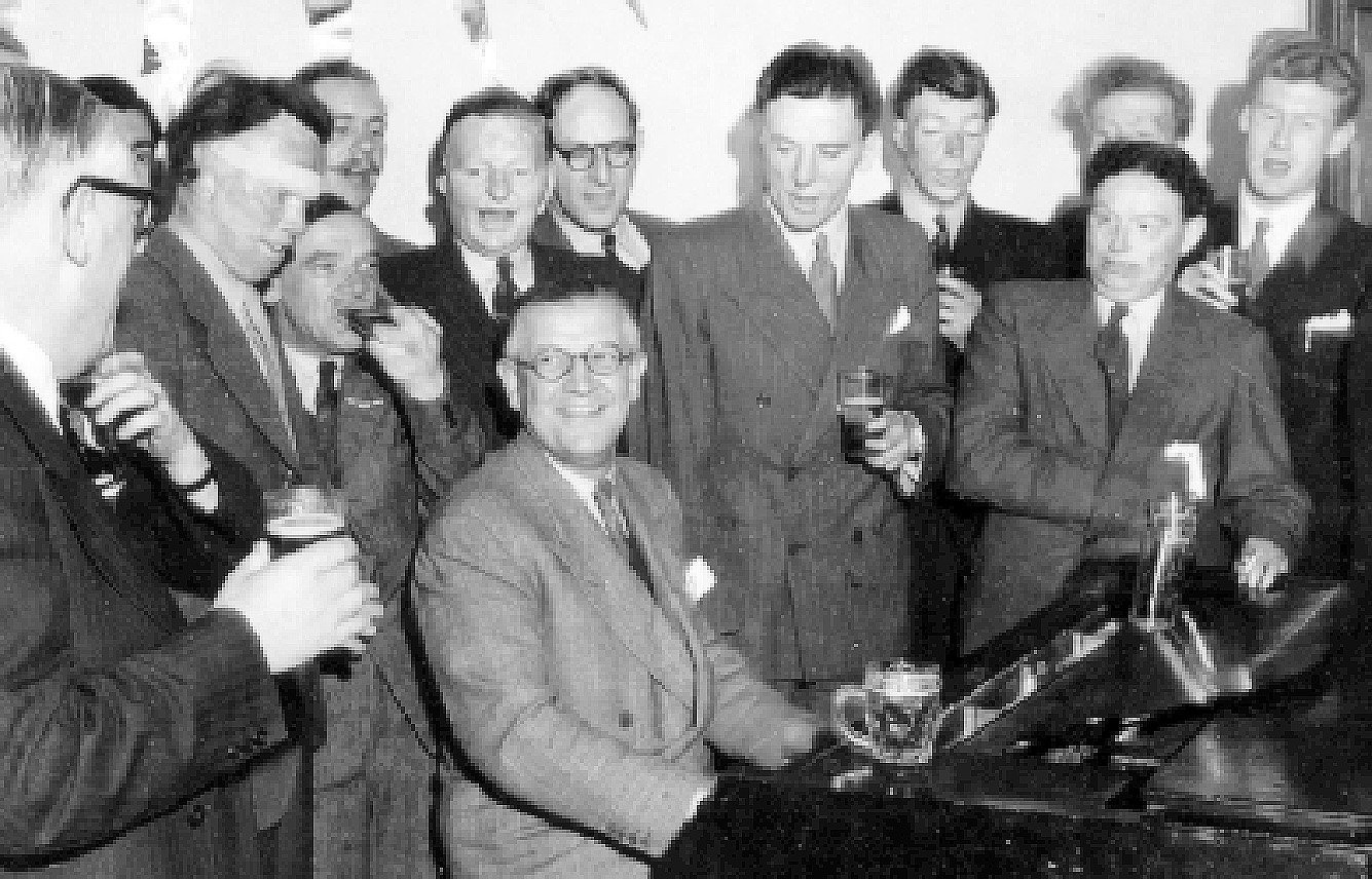Sir Archibald McIndoe plays the piano surrounded by Guinea Pig Club members in 1948. Photo:...
