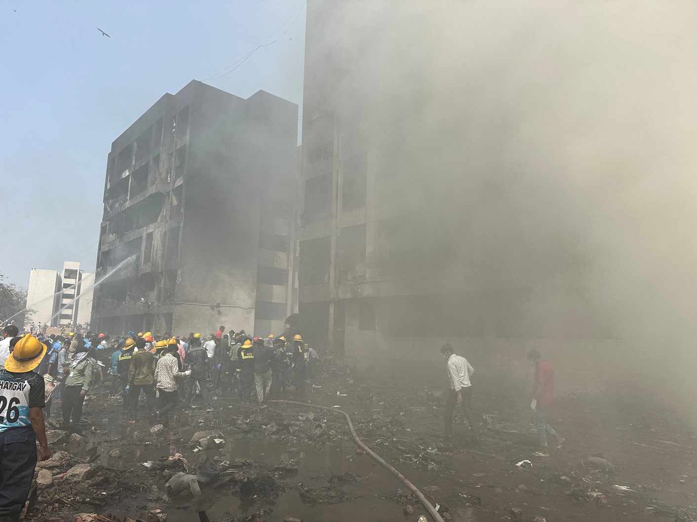 Rescue team members work as smoke rises at the site where an Air India plane crashed in Ahmedabad...