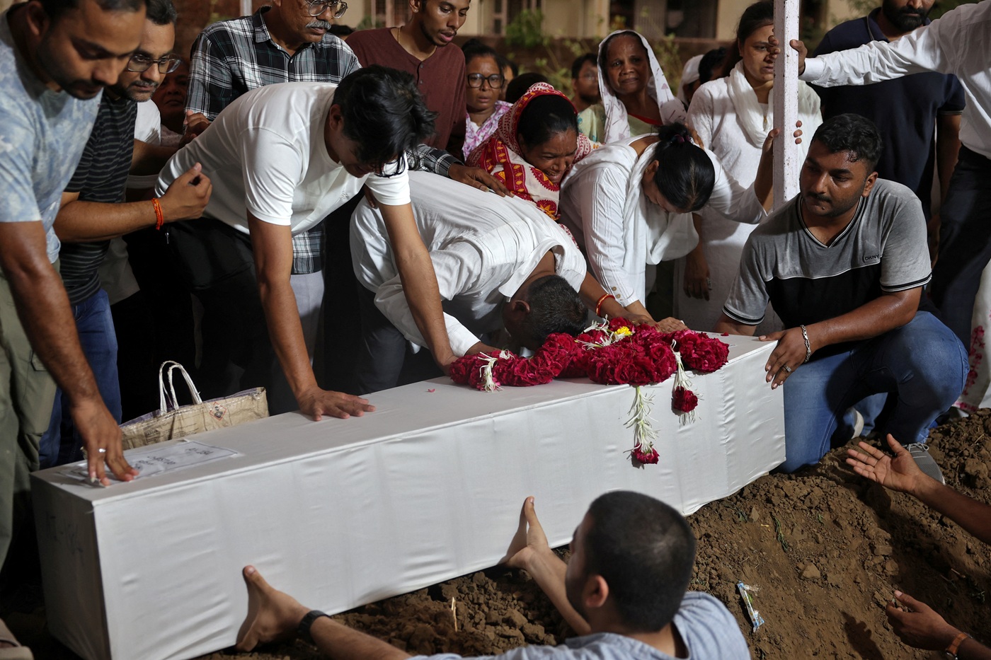 Relatives of one of the crash victims lower a coffin containing his remains into a grave at a...