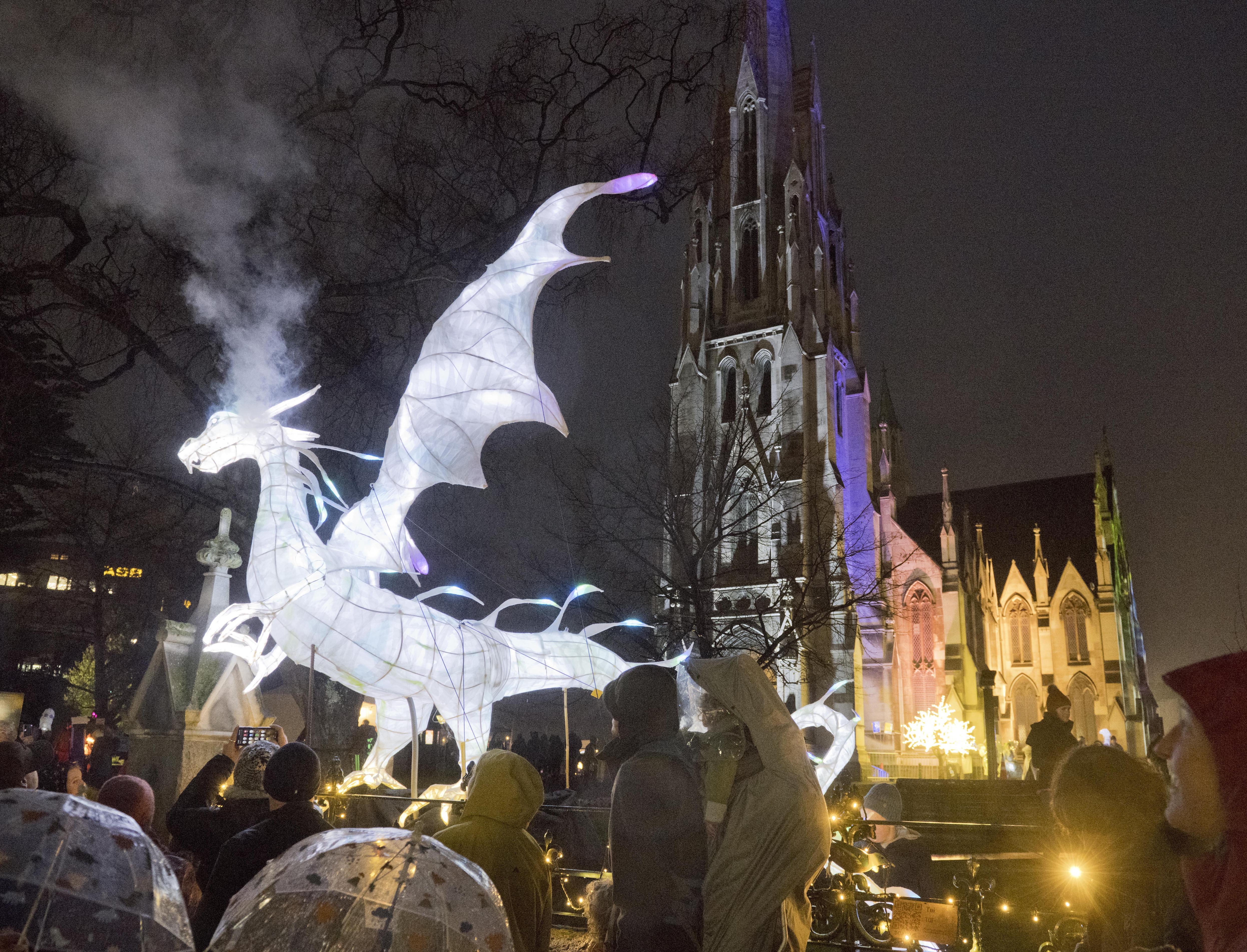 A glowing dragon exhales a smoke cloud over visitors eagerly waiting to be let into the Dunedin...