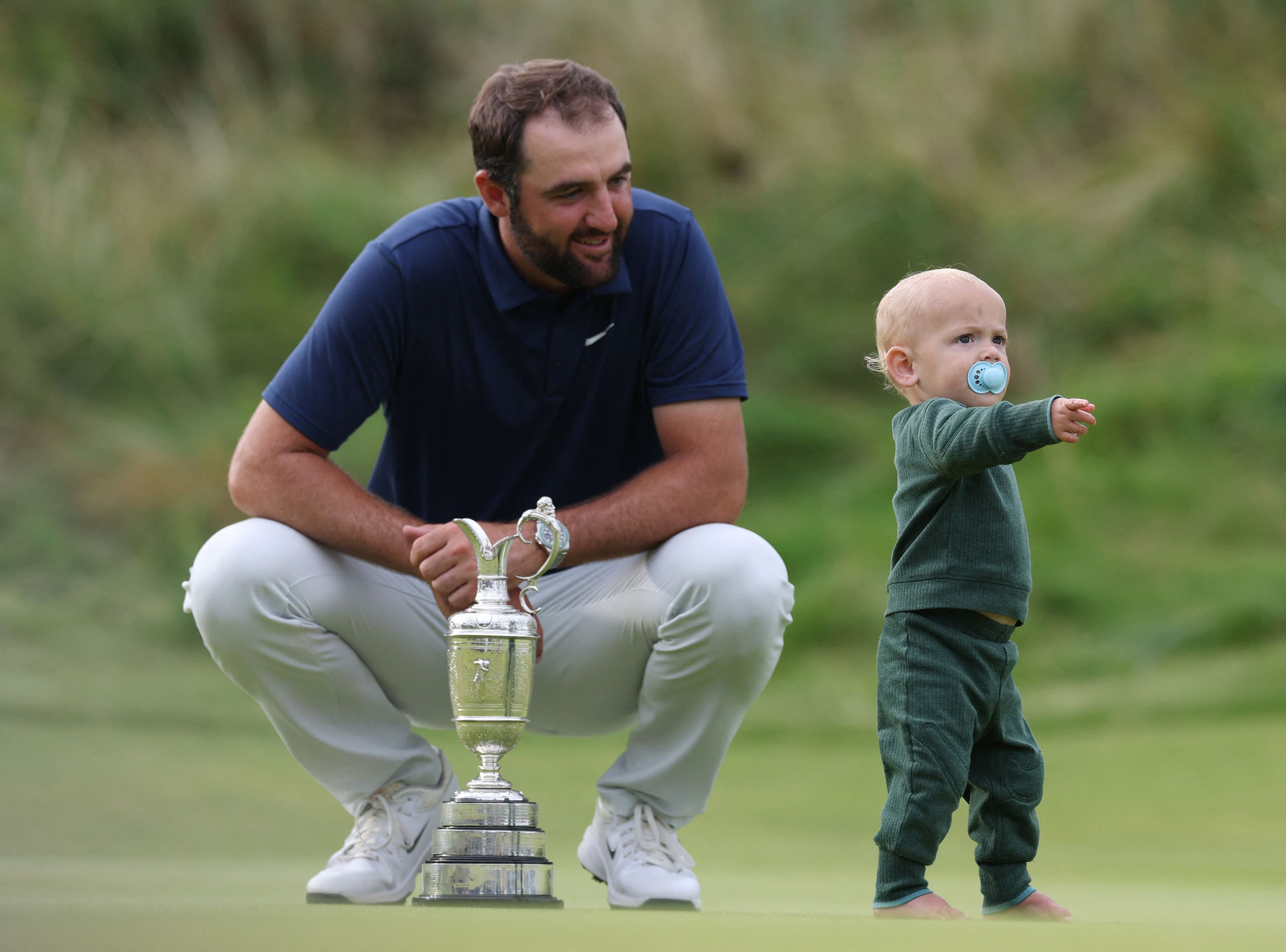 Scottie Scheffler, of the United States, celebrates with his son, Bennett, and the Claret Jug...