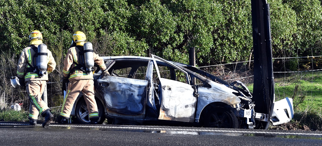 Fire and Emergency New Zealand officers check the car after extinguishing the fire. Photo: Peter...