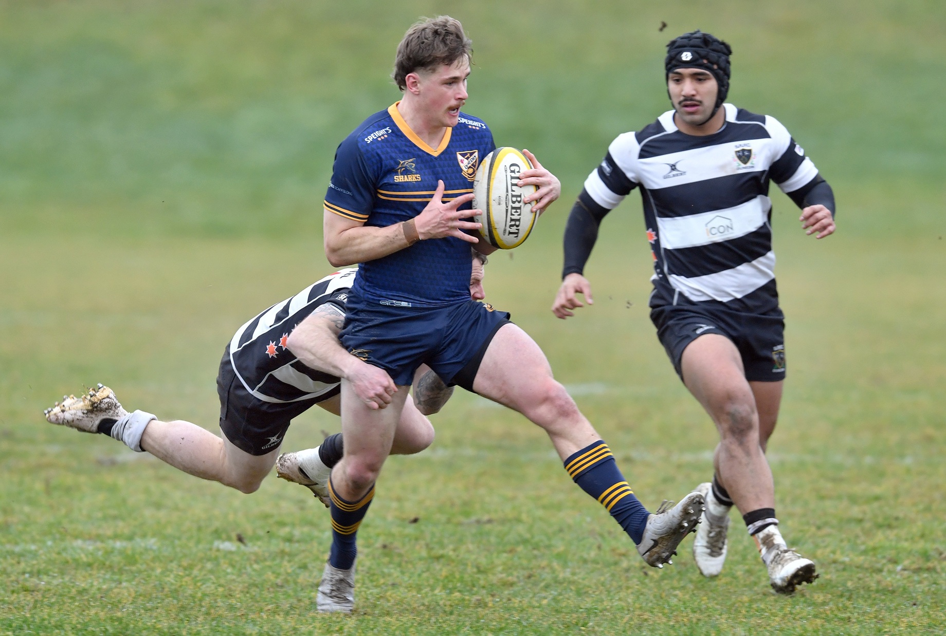 Dunedin first five Cam Burgess stands in the tackle of Southern defender Joshua Buchan and is...