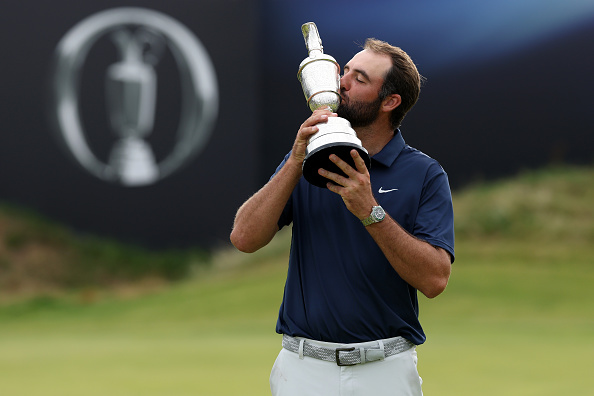 Scottie Scheffler of the United States poses with the Claret Jug on the 18th green after winning...