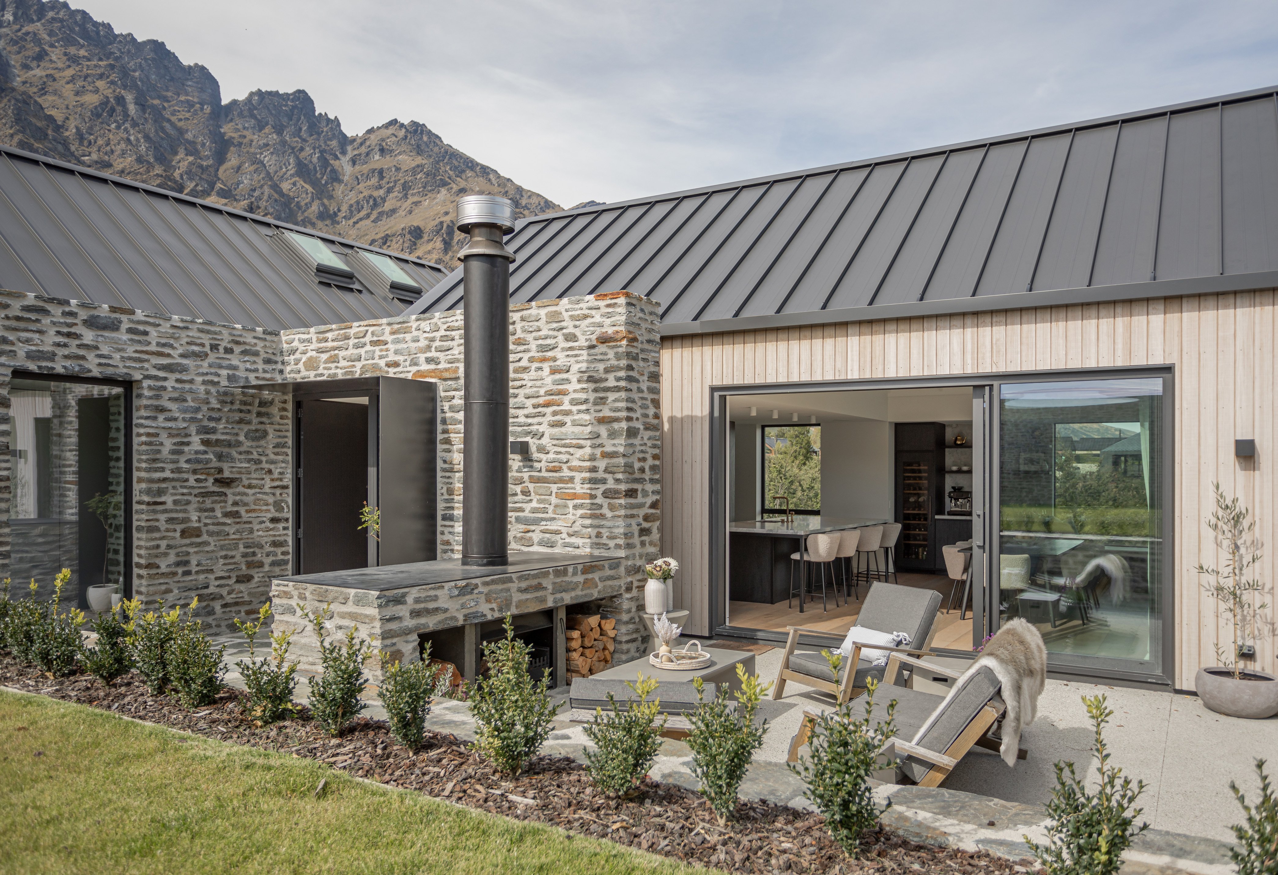 The exterior of the house features stone walls, Abodo timber cladding and an outdoor fireplace....