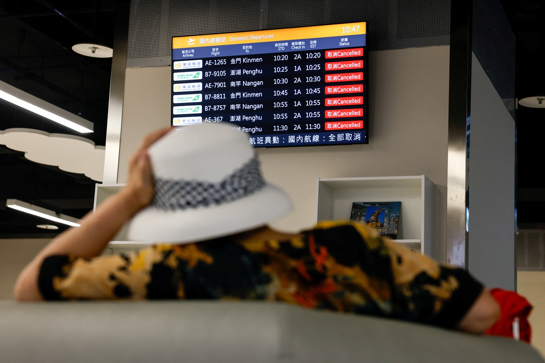 A woman sits in front of a screen displaying information on cancelled domestic flights at an...