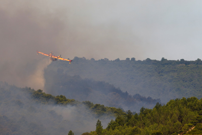 A Canadair firefighting plane drops water during a wildfire near Saint-Laurent-de-la-Cabrerisse,...