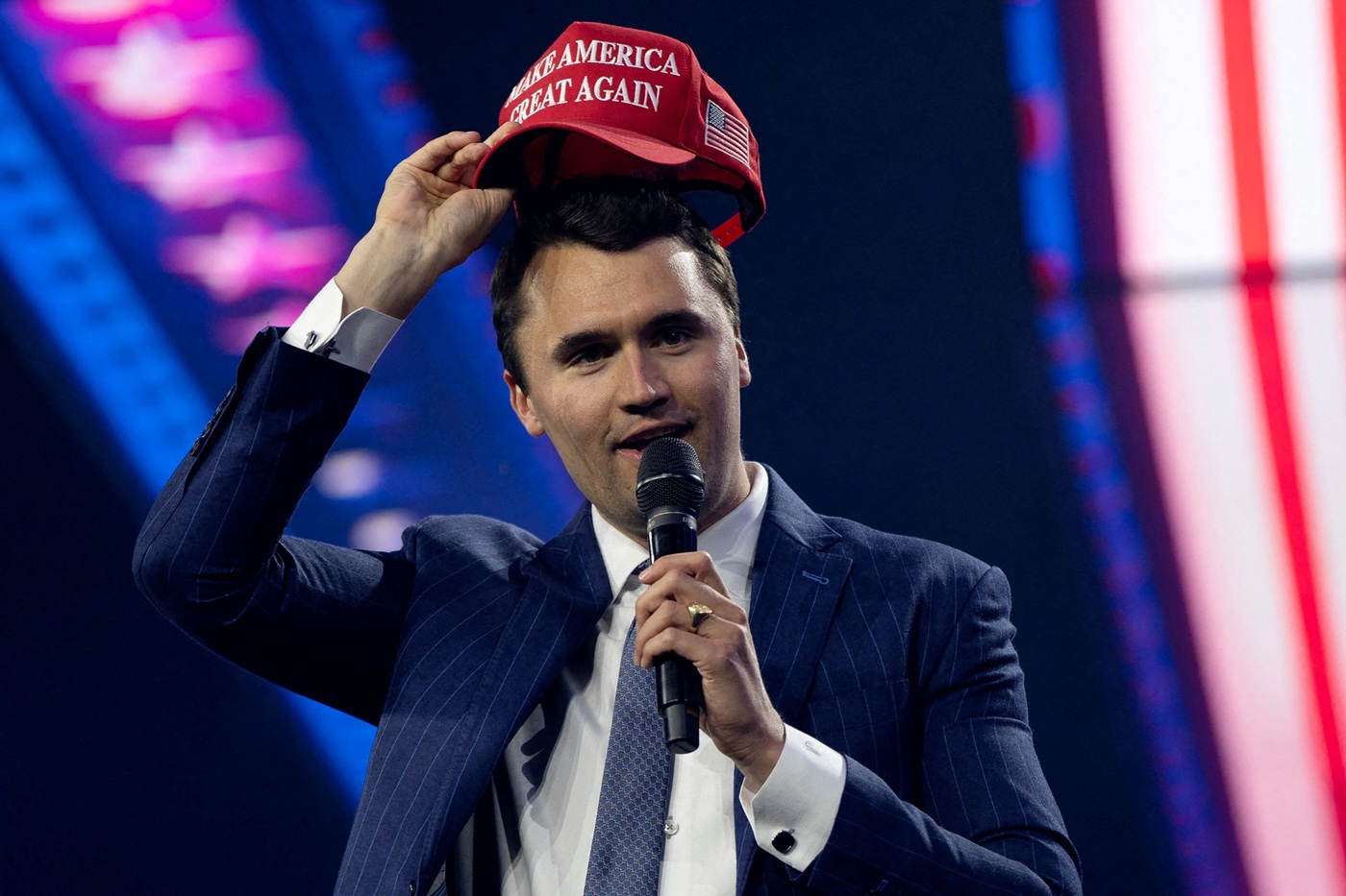 Charlie Kirk puts on a MAGA hat during the AmericaFest 2024 conference in Phoenix, Arizona in...