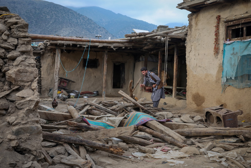 A man looks for his belongings amidst the rubble of a collapsed house after the earthquake that...