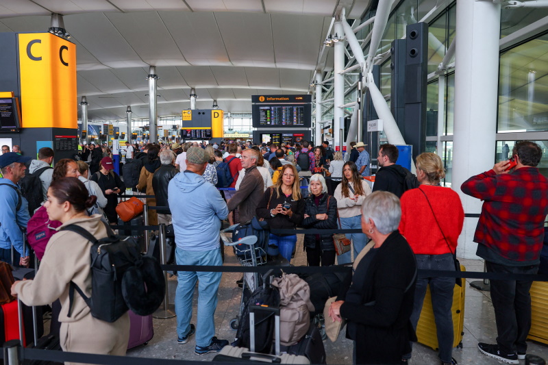Travellers wait yesterday near a check-in area at Heathrow Airport Terminal 2, amid flight delays...