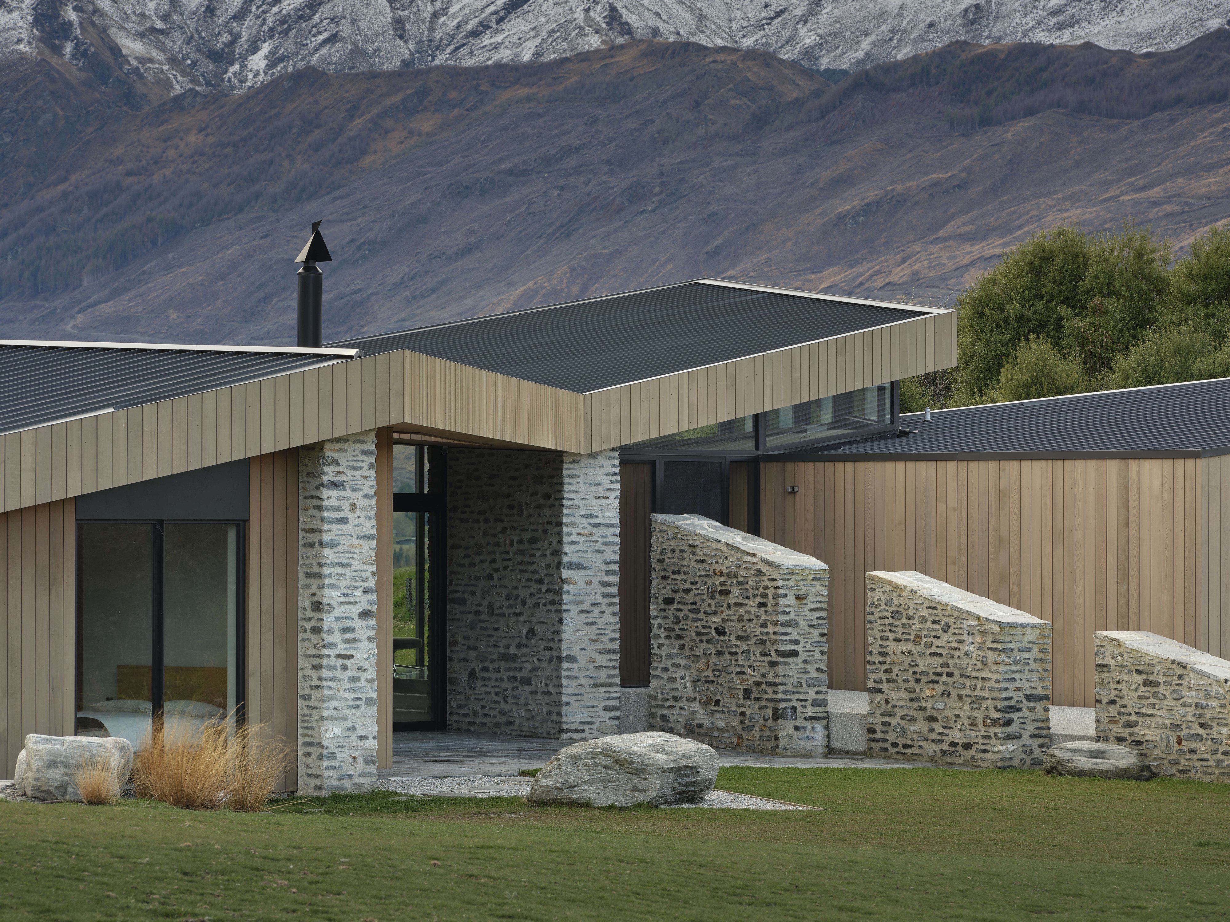 Stone walls extending from the house strengthen its visual connection with the landscape, while...