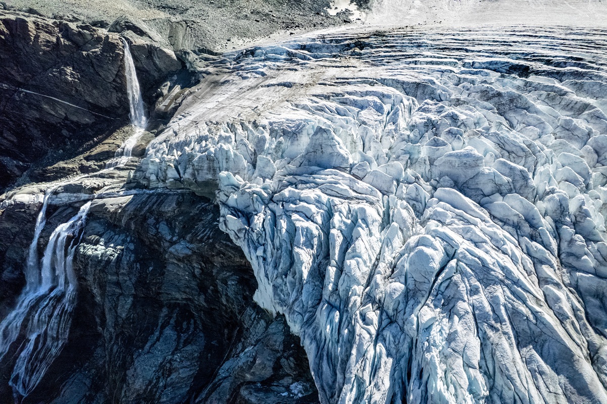 A drone view shows water from melting ice running down the side of the Turtmann glacier on a warm...
