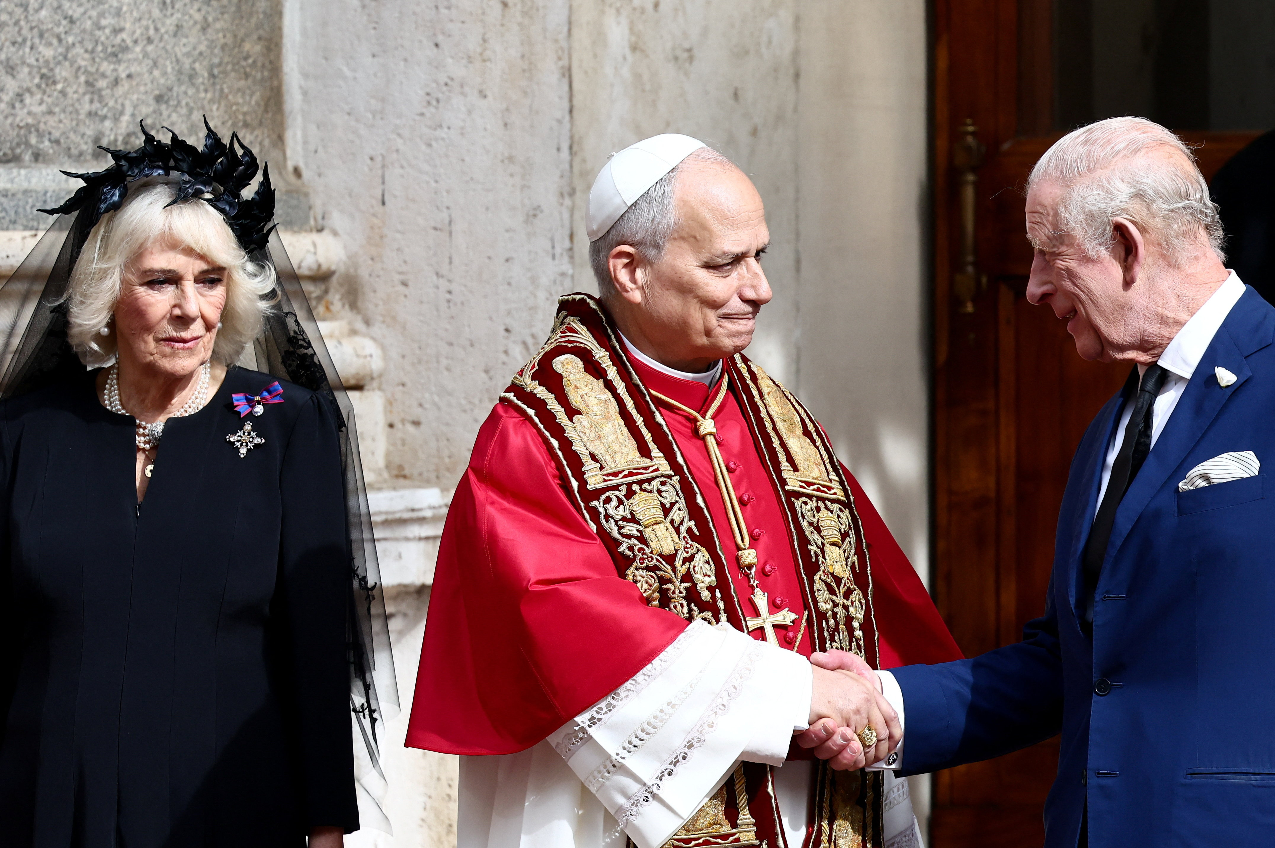 King Charles shakes hands with Pope Leo XIV, as Queen Camilla stands next to them, following an...