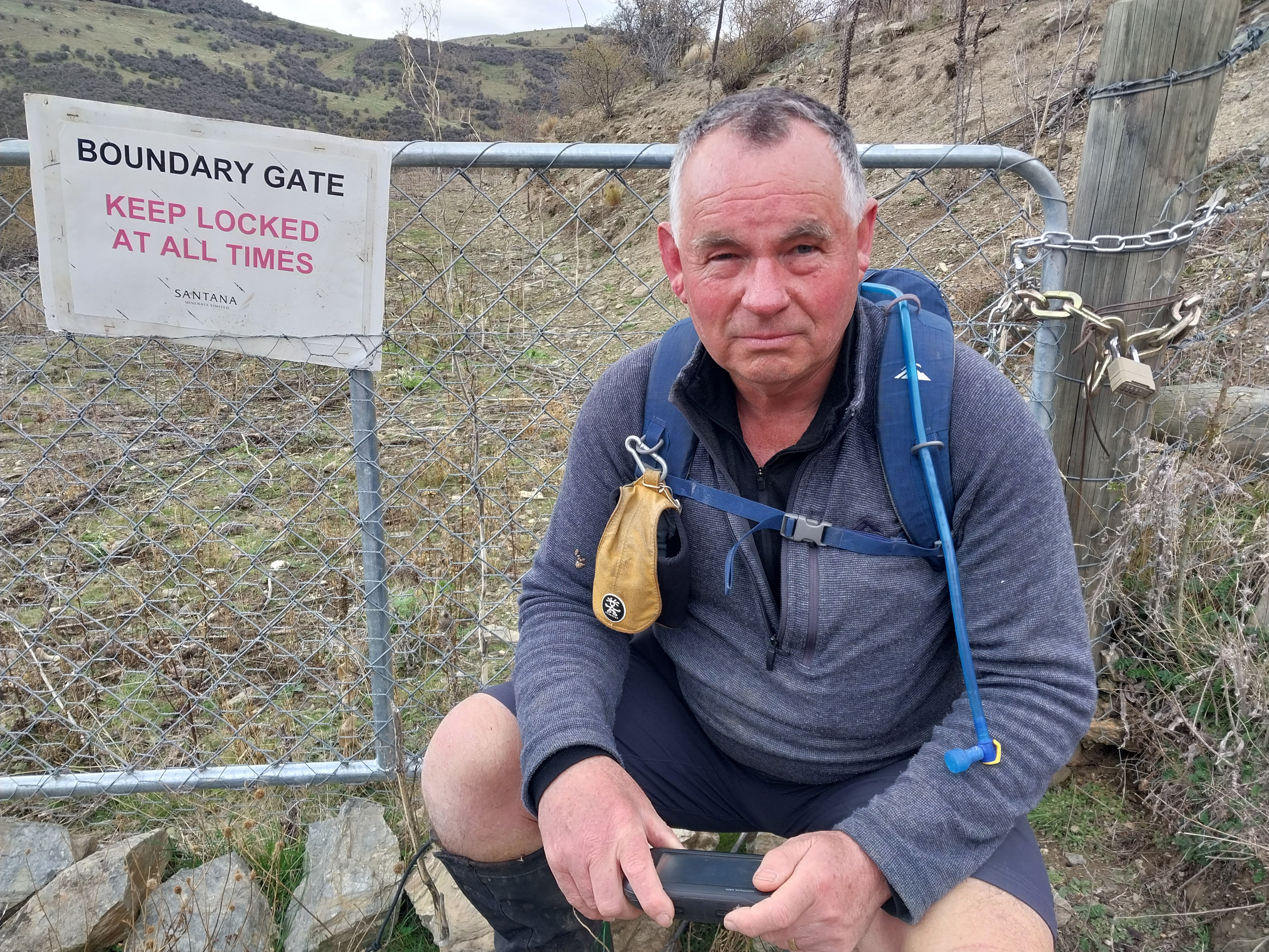 Archaeologist Matt Sole by a locked gate, with a Santana-branded sign, barring his way on the...