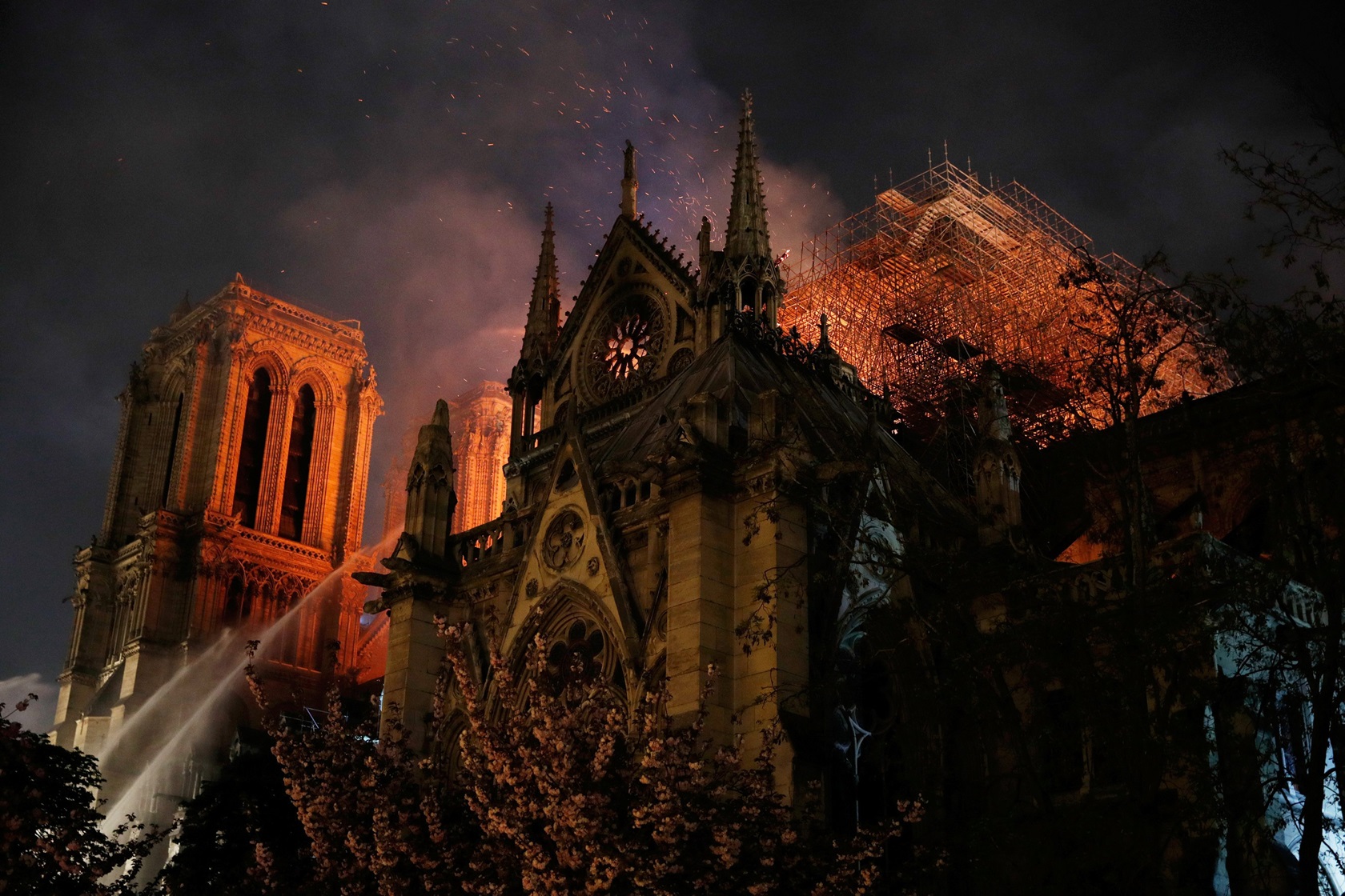 Sparks fill the air as Paris fire brigade members try to extinguish flames as Notre Dame...
