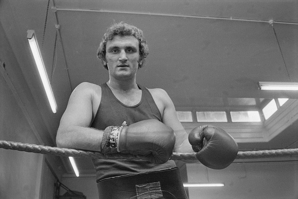 Hungarian-born British-Australian boxer Joe Bugner rests his gloved hands against the ringside...