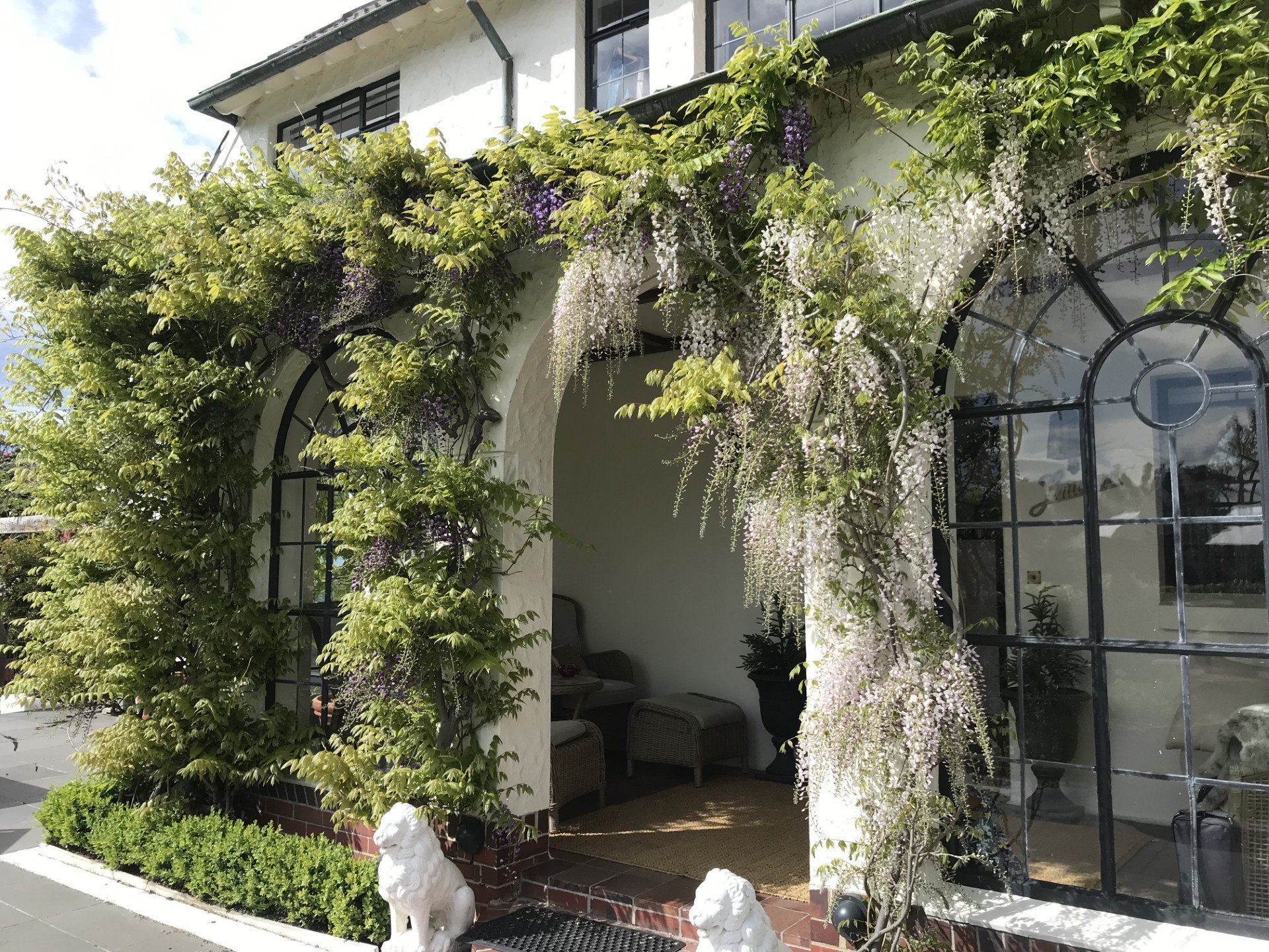 White and lavender wisterias drape the front entrance.

