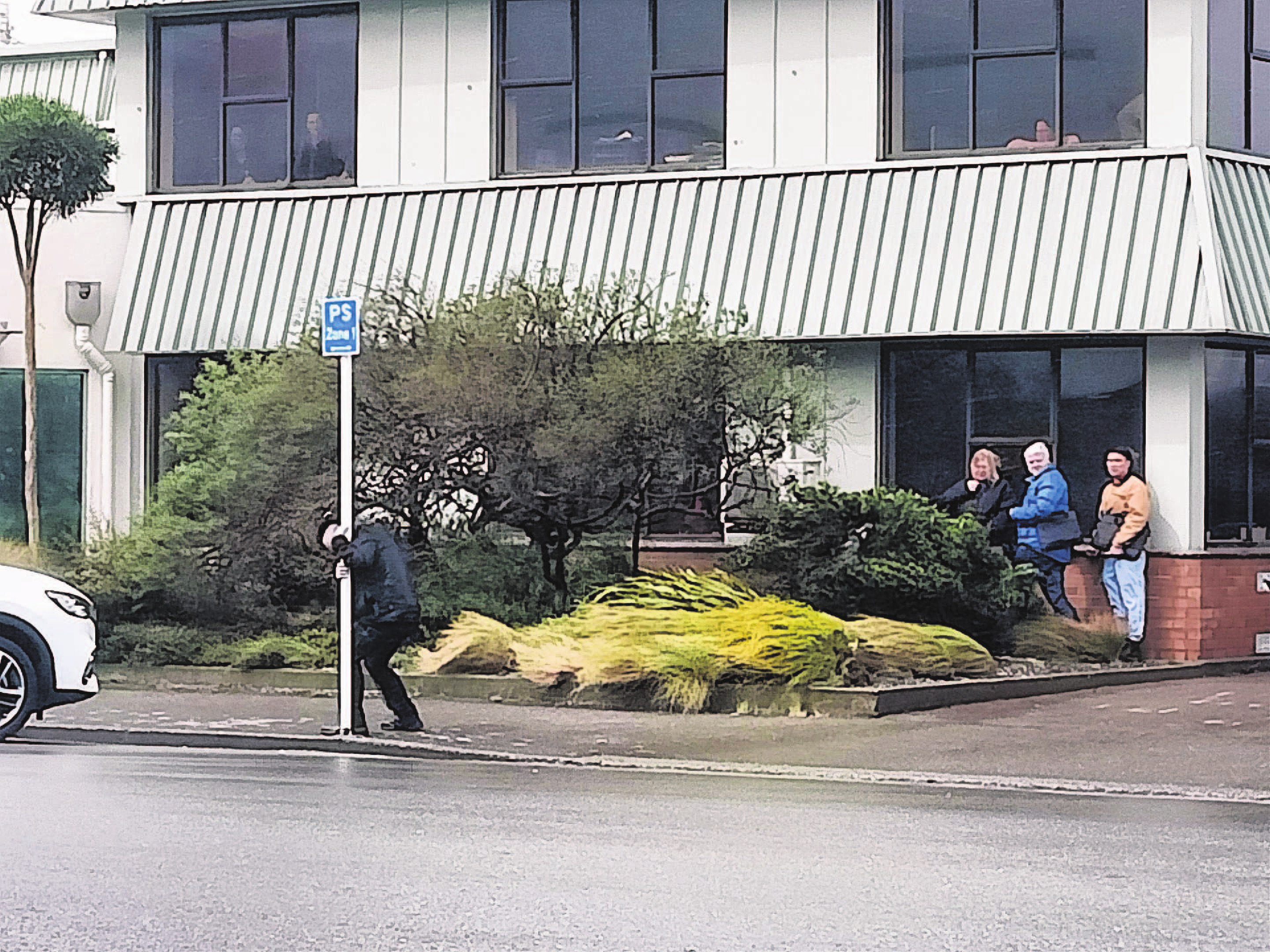 A woman clings to a pole in Invercargill during the high winds. Many businesses closed for the...