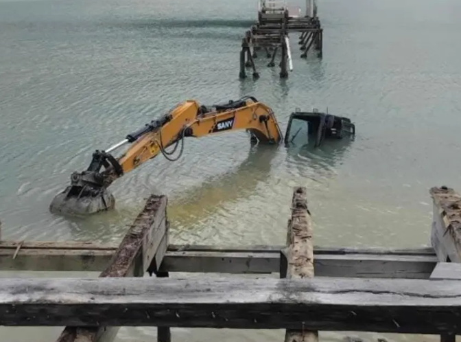 A digger working on the replacement of Waitaria Bay's new jetty has become stuck in the sand and...