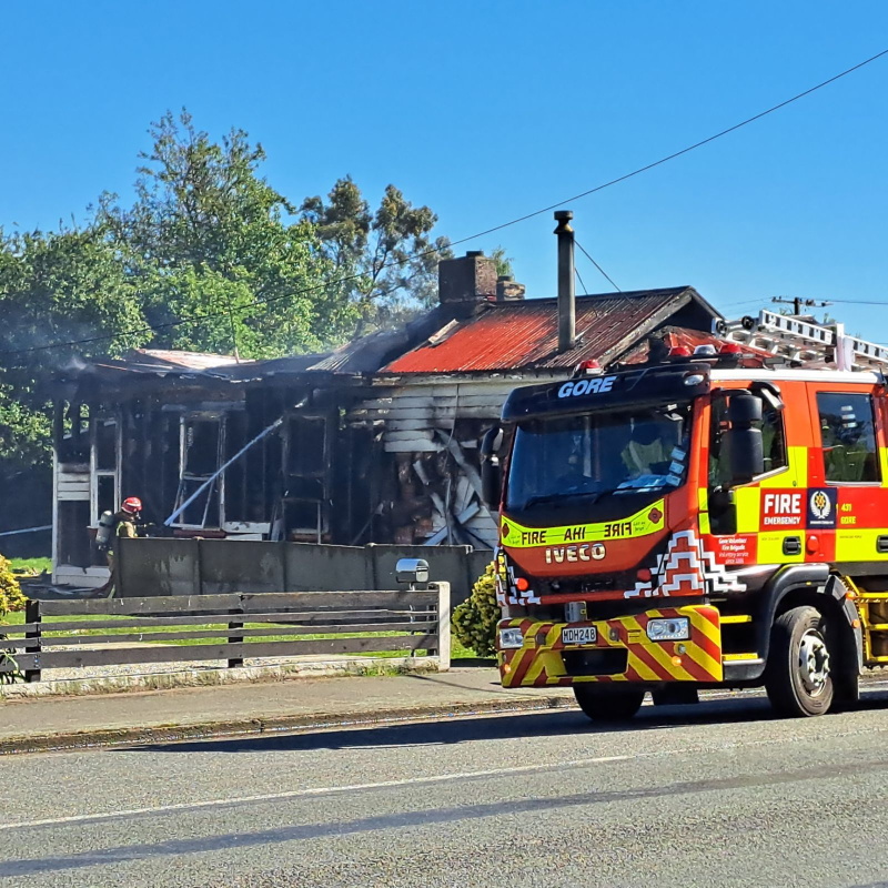 Fire crews outside the house that was destroyed in Mataura this morning. Photo: Gerrit Doppenberg
